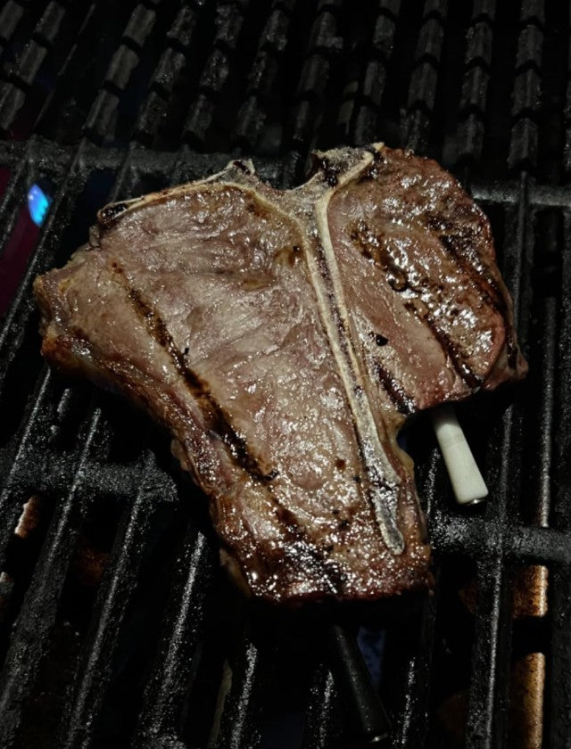 Wireless Meat Thermometer Inserted in T-Bone Steak on the Grill